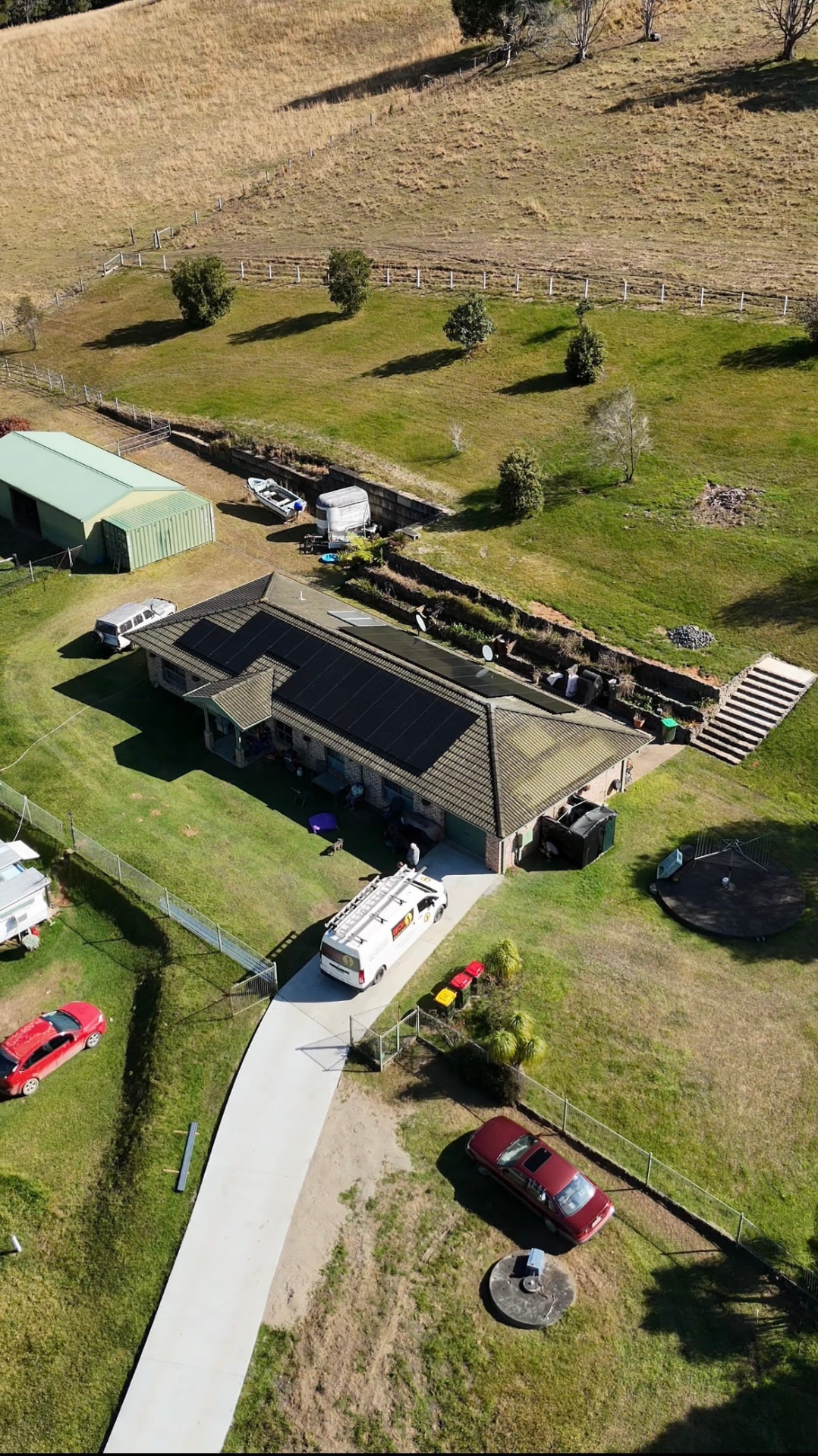 Aerial view of a rural Coramba home with a full black solar array on the roof and a Gecko service van in the driveway