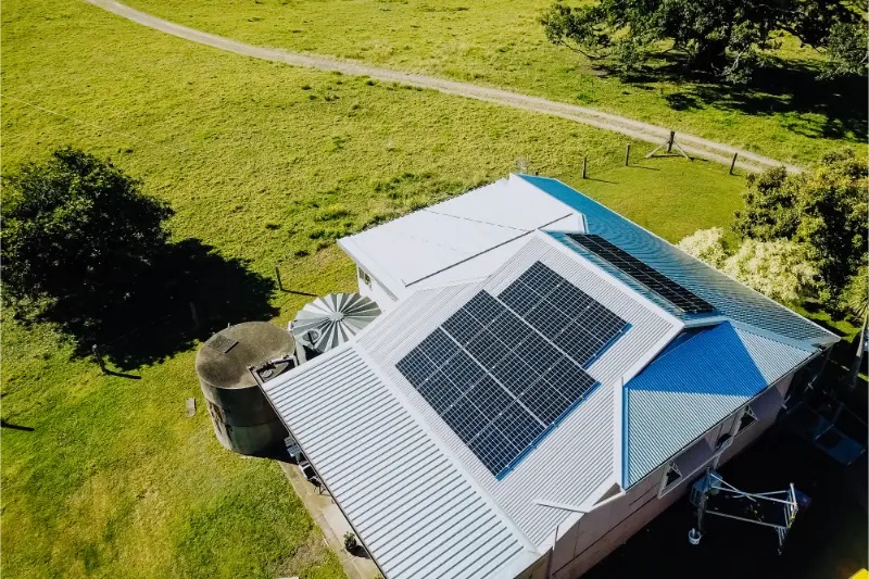 Aerial drone view of solar panels installed on a white corrugated metal roof of a rural Bowraville property.
