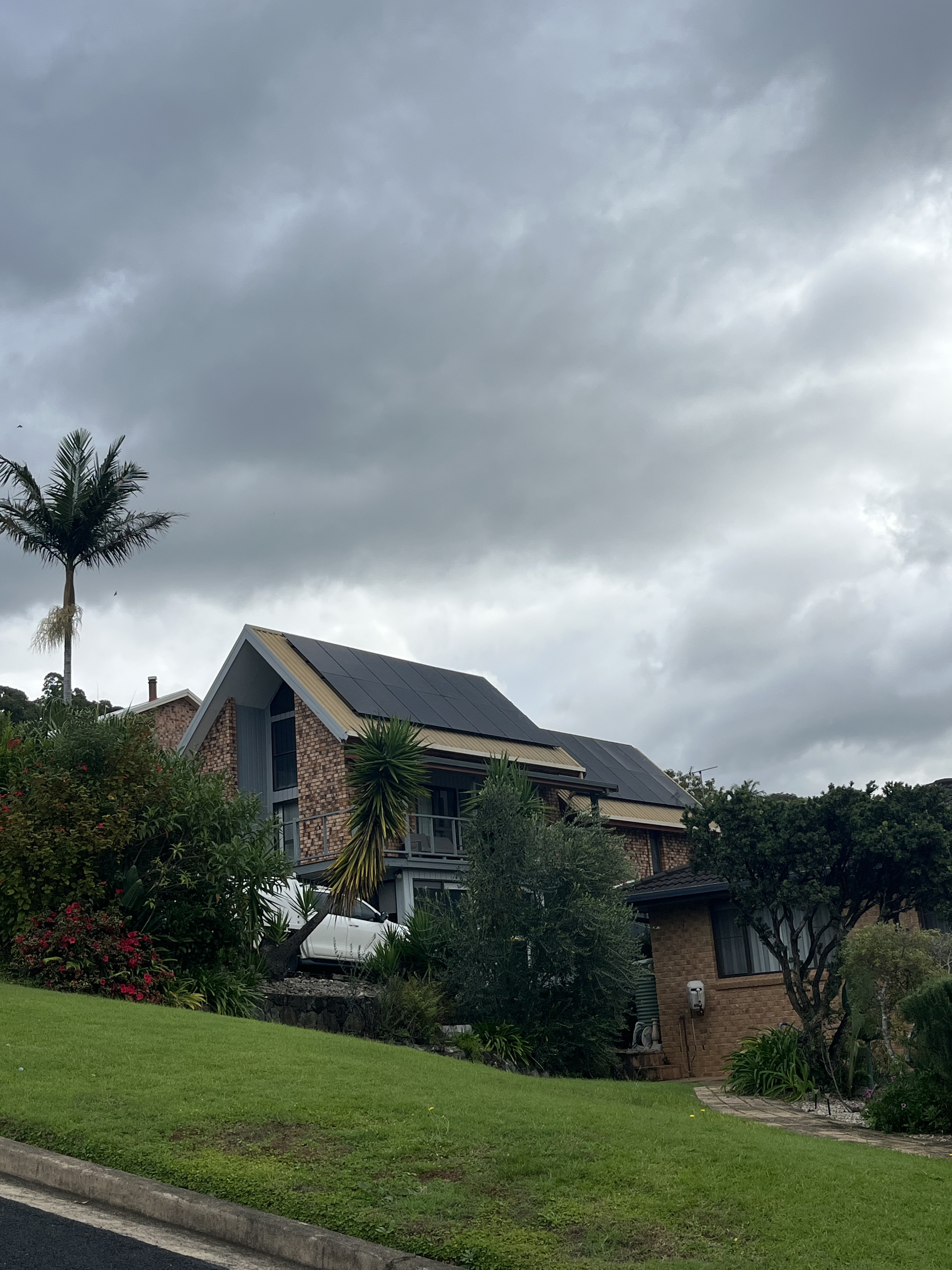 Black solar panels on a brown-tiled brick home